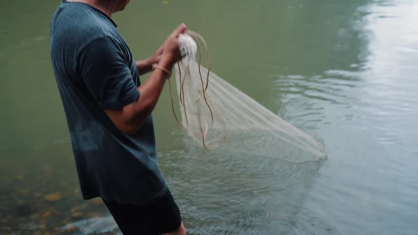 Fisherman in a lake collecting a fishing net