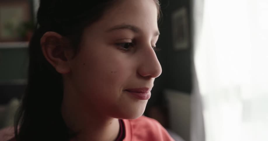 Girl with happy facial expression is sitting at a table typing on a laptop