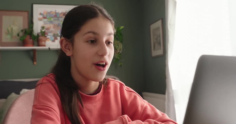 Girl sitting in a room interacting with a laptop open in front of her