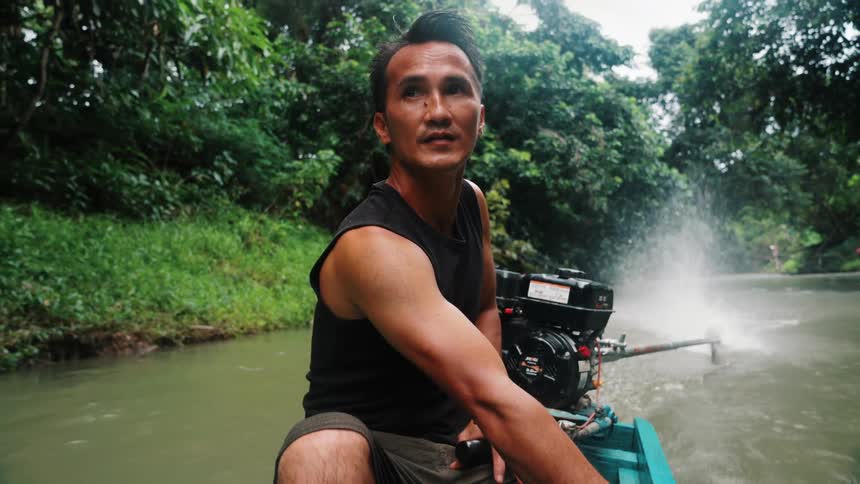 Man driving a wooden boat on a river