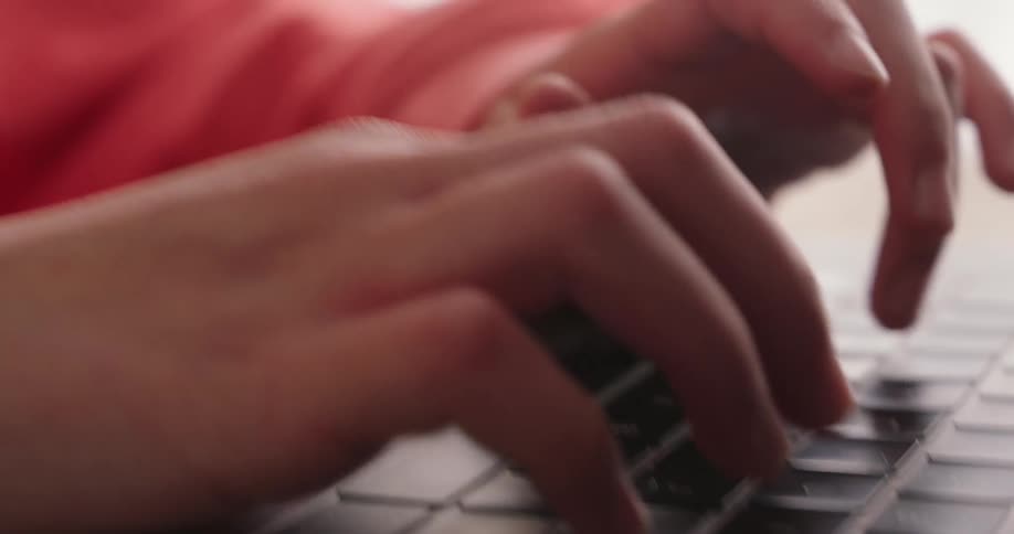 A girl in a room types on a computer keyboard