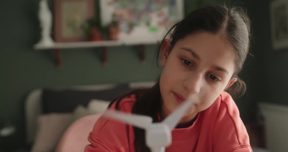 Portrait of a girl sitting looking at a wind power model