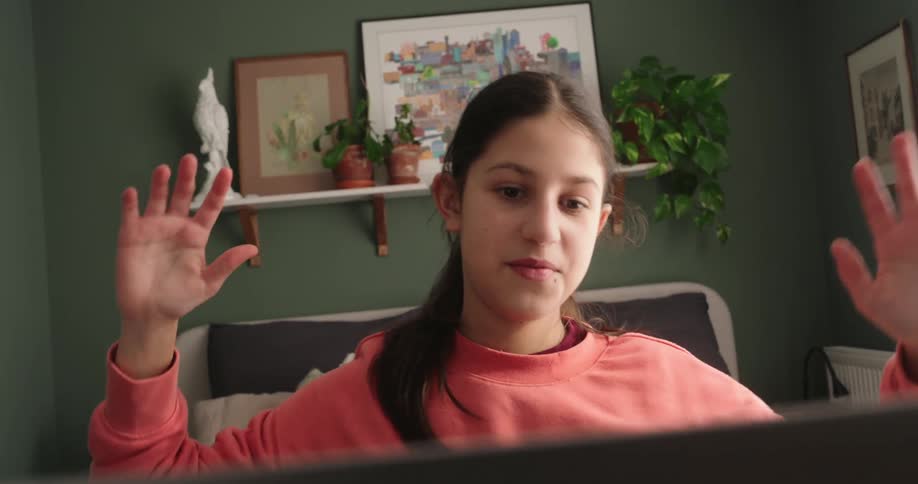 A teen girl is chatting online on the computer while sitting at a desk in her bedroom