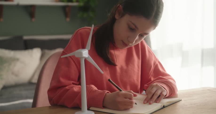 Girl sitting at a table writing in a notebook