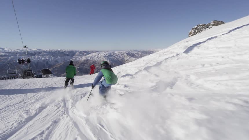 Skiers speed down a snowy mountain