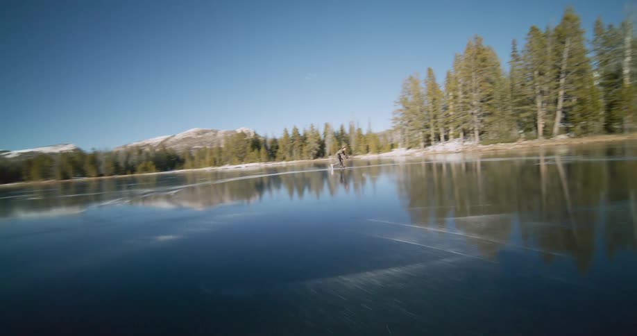 A man is in a forest ice skating on a frozen lake