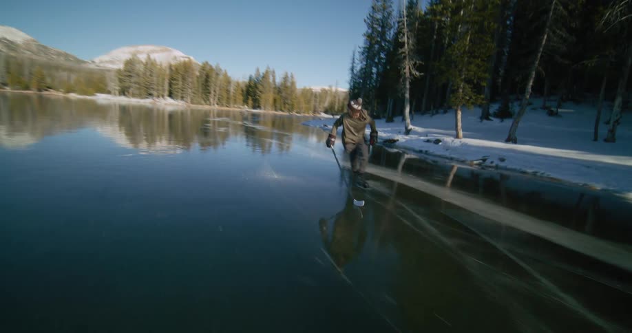 Man skating on frozen lake with hockey equipment