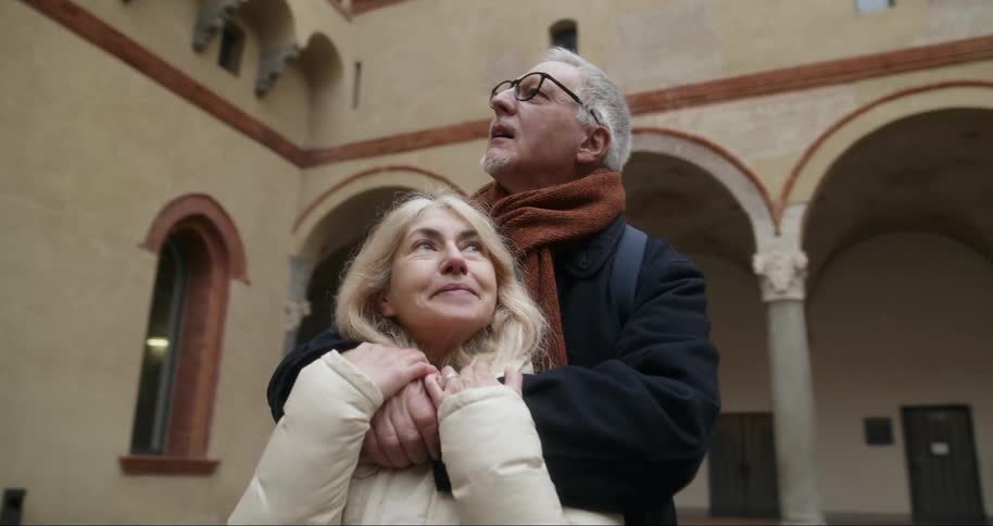 Elderly couple hugging together in a classical architectural setting