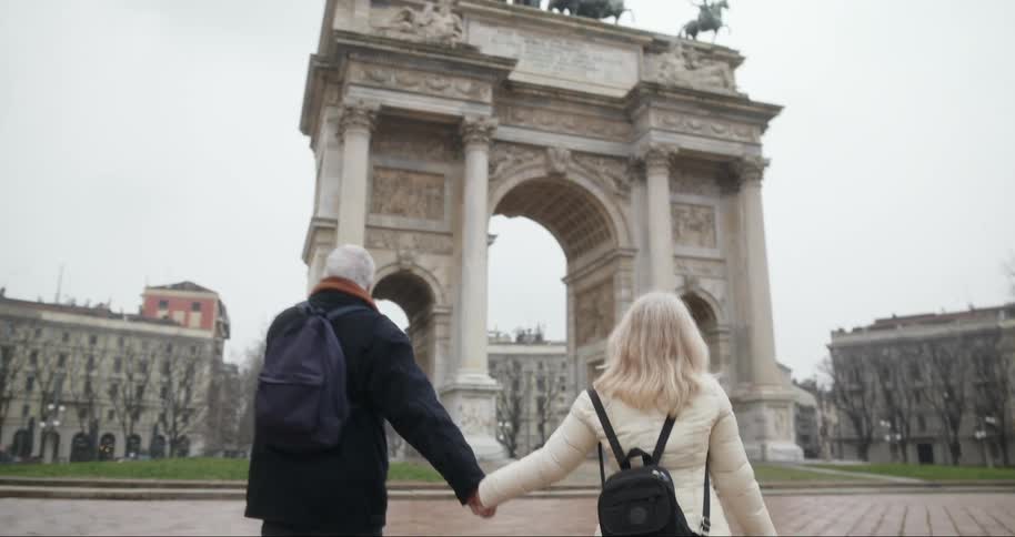 Two tourists hold hands and walk towards the monument