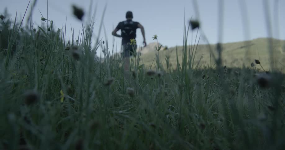 Legs of a person running through grass during the day