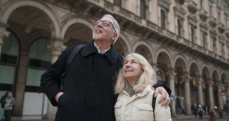 A man and woman hug and point up at the buildings