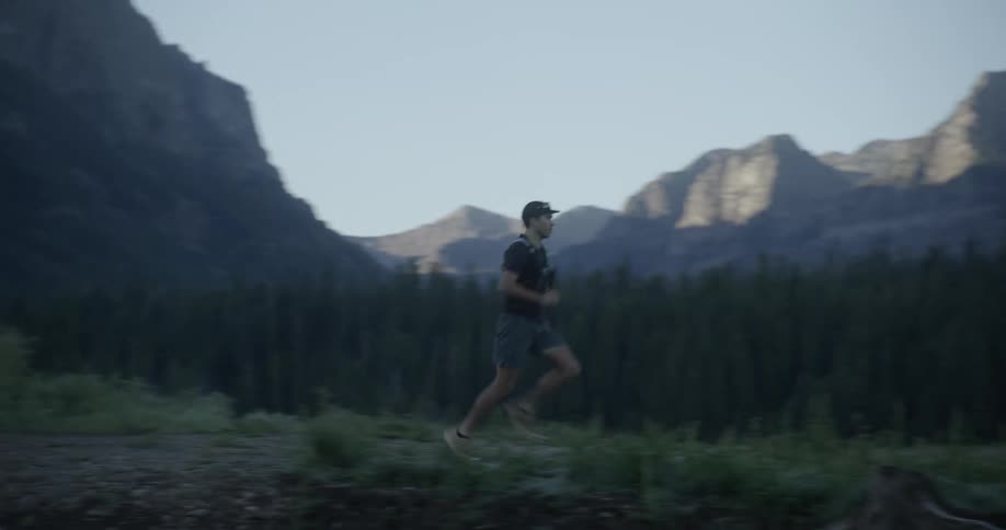 A man is running past the forest and mountains