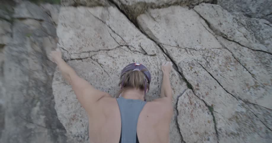 A woman is rock climbing towards the cliff edge