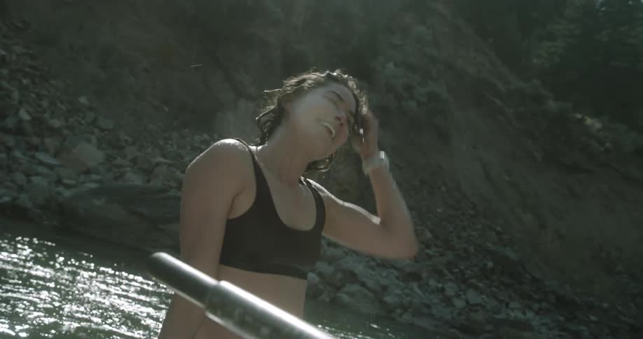 A woman pushes her hair back as she sits on a boat in a river