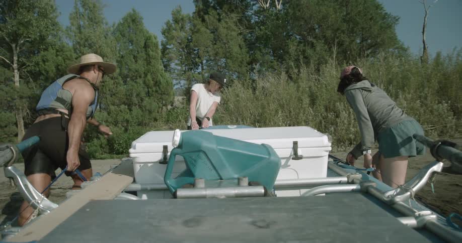Three people pulling a boat out of the lake