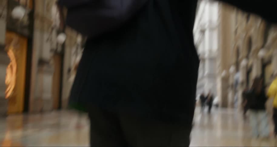 Wife watches her spouse spin on a mosaic decorating the floor between buildings connected with an arch