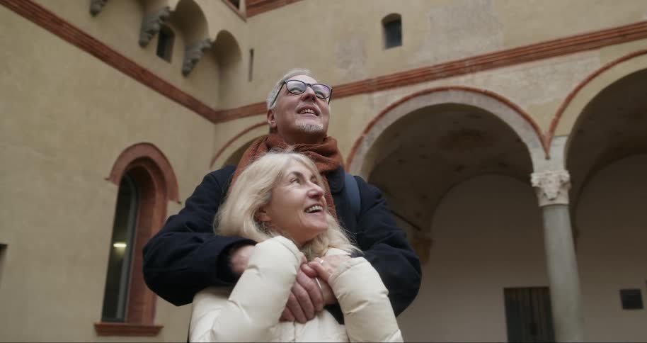 Elderly couple smile as they enjoy the architecture of a historic building