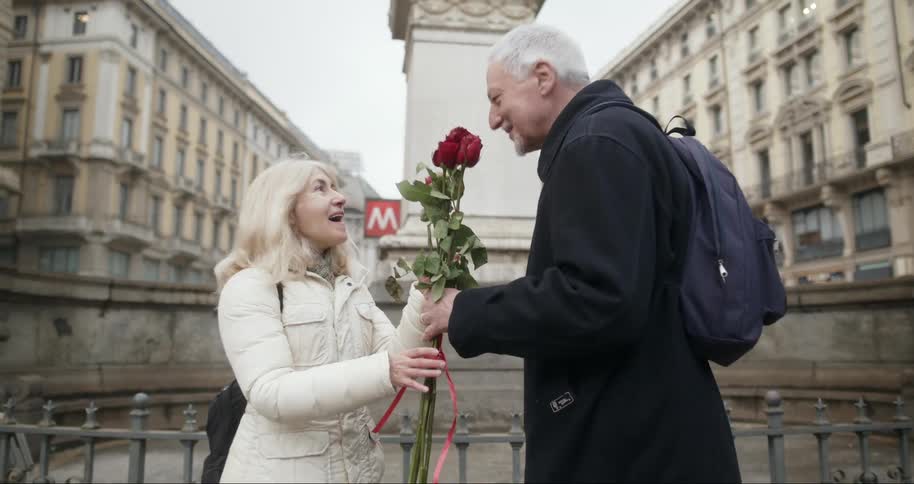 Elderly man giving roses to his wife who is happy with the surprise