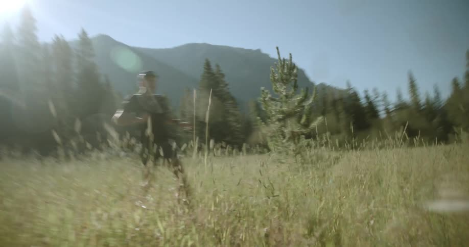 A man is running through the long grass on a sunny day