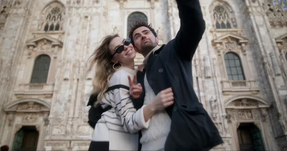 A man and woman take a selfie in front of the large church