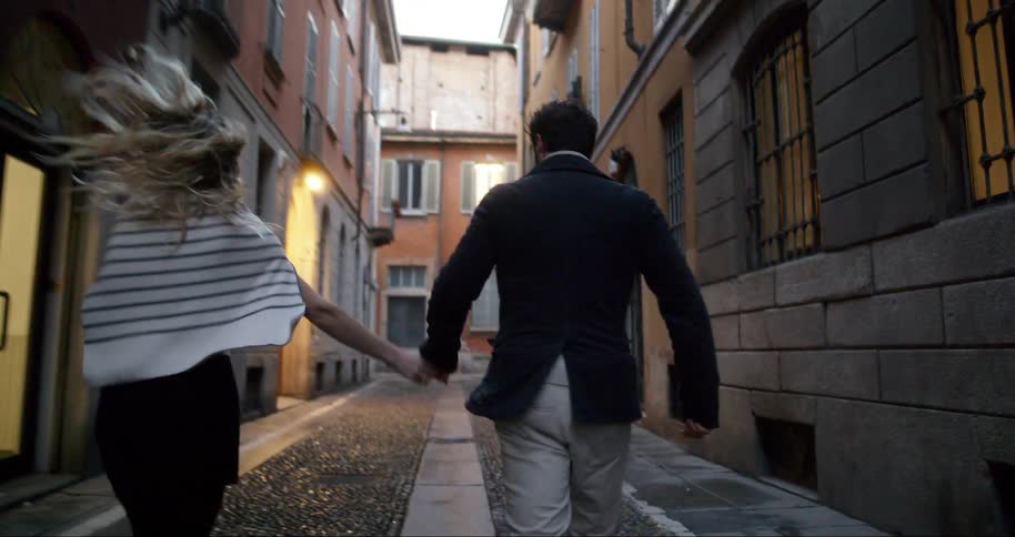 Woman and a man holding hands running down an urban hallway