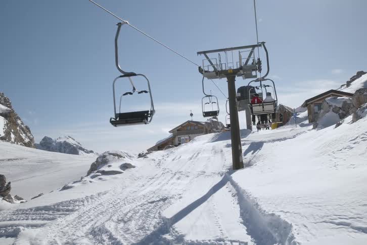 People riding a cable car through the snowy mountains