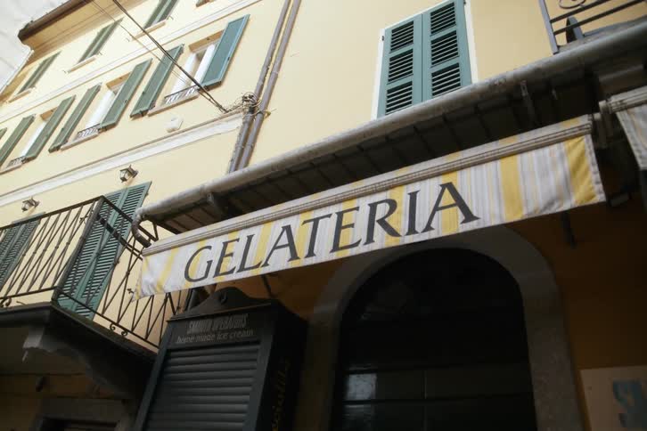 The facade of a small orange shop that is closed and with a sign with black writing