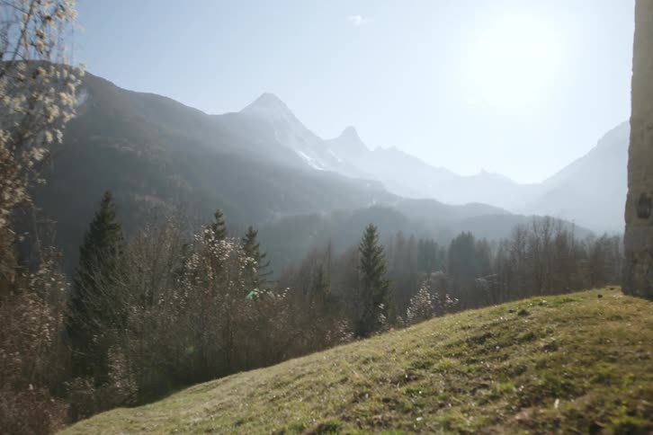 Landscape of a hill surrounded by trees and silhouette of mountains in the background