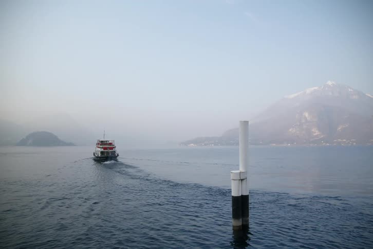 Boat traveling across the ocean with mountains in the background