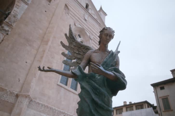 Artistic monument of an angel in the open air surrounded by classical buildings