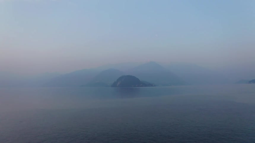An island in the middle of the sea that is partially covered by fog