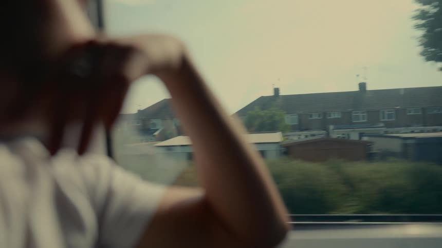 Person looks out the window while riding on a transport passing through a residential area
