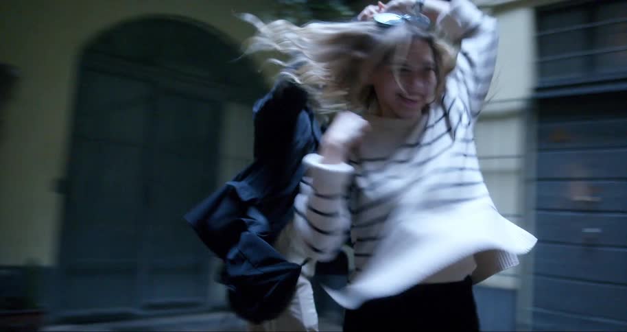 A young couple runs through the lobby or courtyard of a building holding hands and having fun