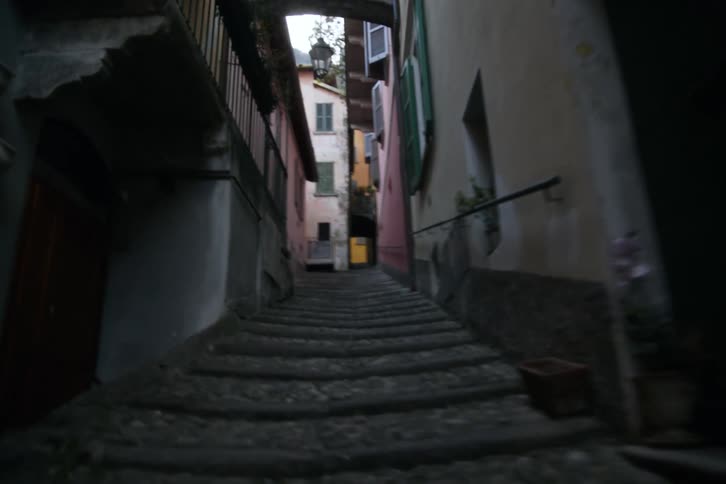 Apartment entrances border a narrow sloping path passing between buildings in a residential neighborhood