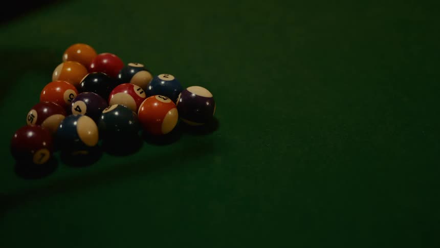 A person sets the pool balls on the table