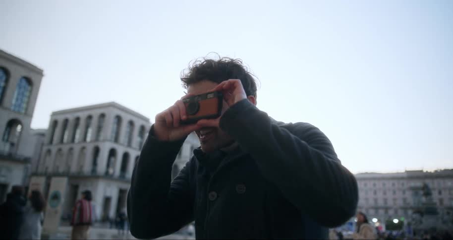 Man in a square taking pictures with a small camera