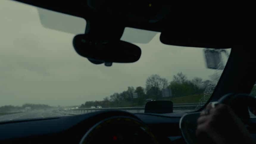 Pair of hands on steering wheel driving a vehicle on a highway