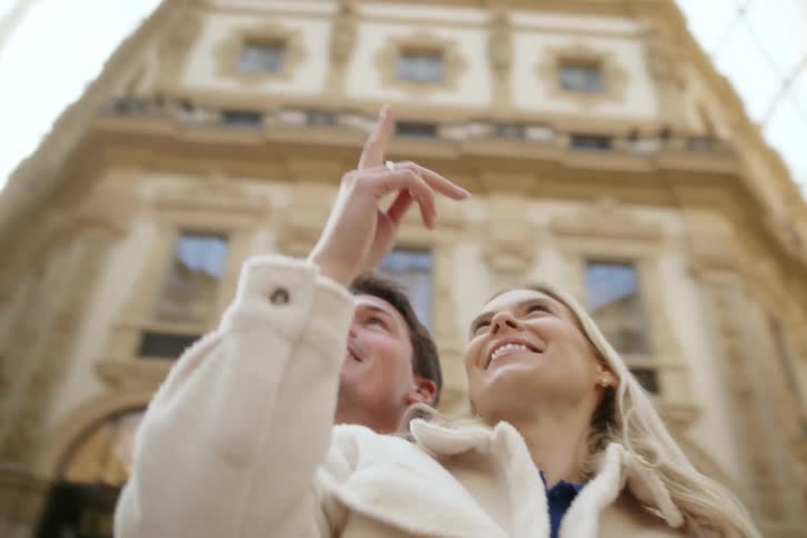 Couple hugging each other while standing inside a classic building with a glass roof
