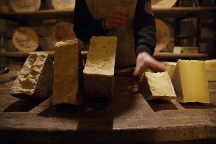 Arranging various blocks of cheese on a wood counter