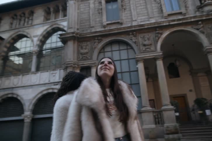 Two women holding hands enjoying the view of buildings with classical architecture around them