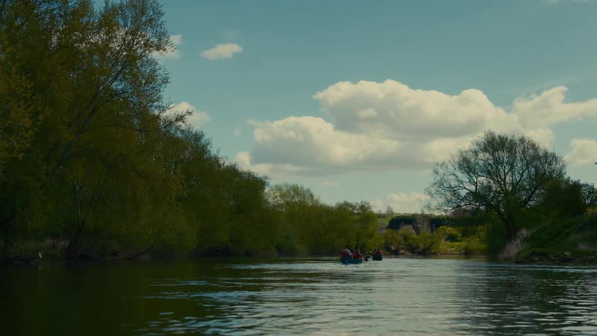 Group of people rowing a boat down a river surrounded by vegetation