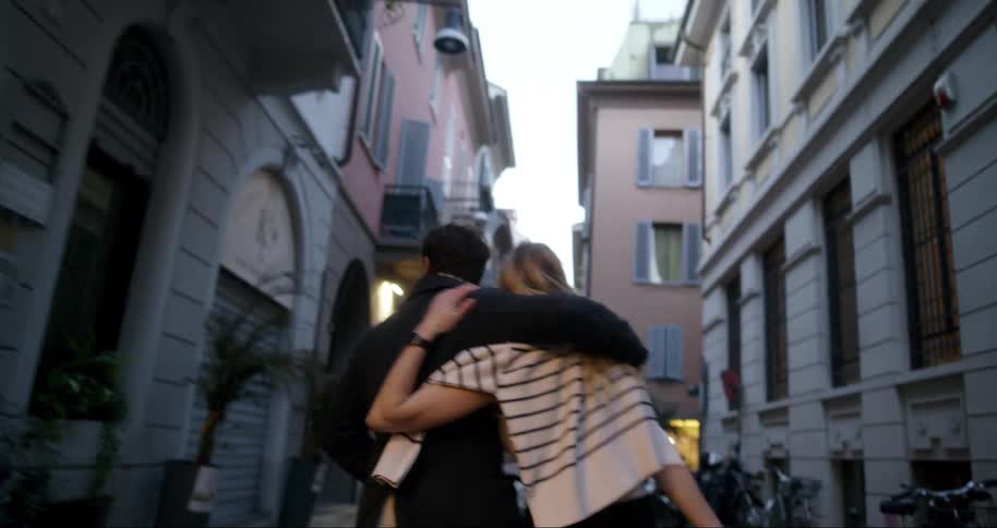 Couple walking arm in arm down an urban hallway