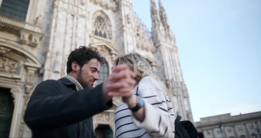 Happy couple holding hands dancing in front of a classic cathedral
