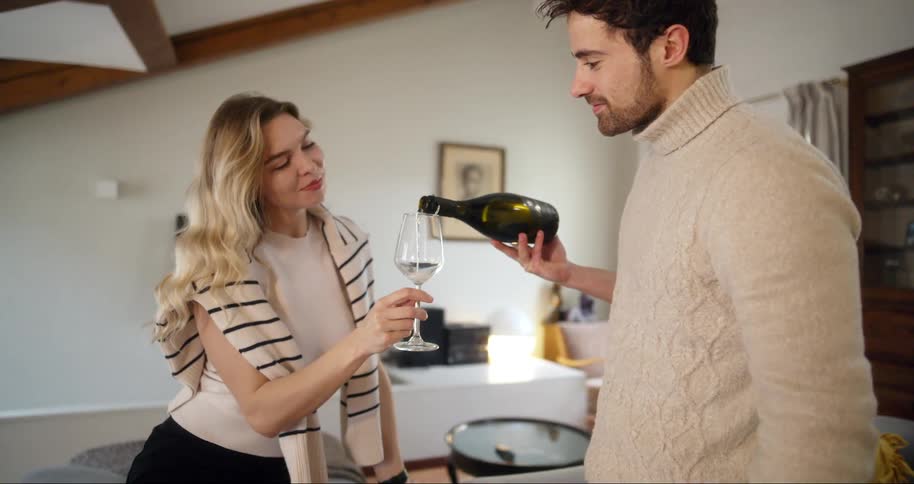 Man serving champagne in a glass to a blonde woman who is sitting