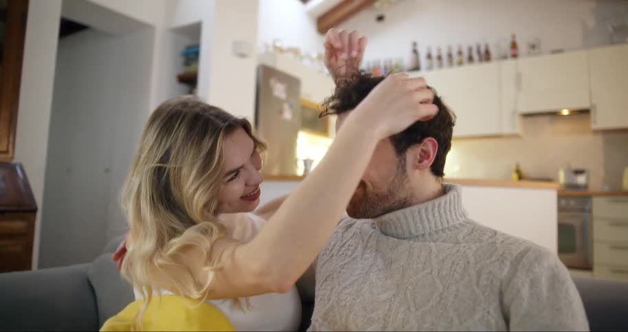 A couple are hugging and sitting on the couch