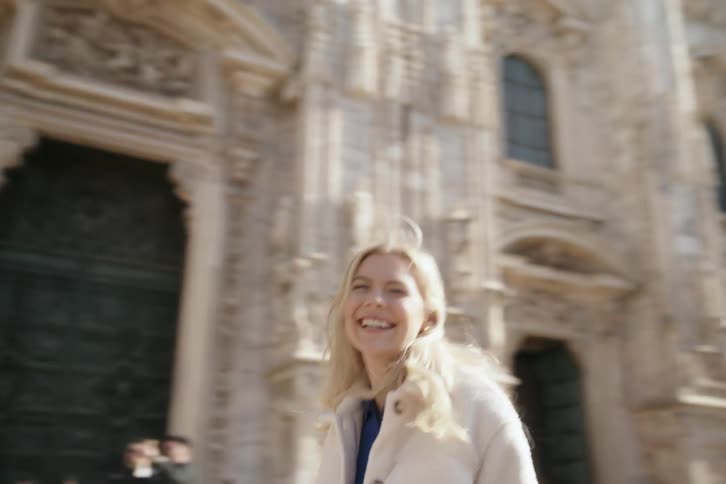 Happy blonde woman standing next to a classic cathedral