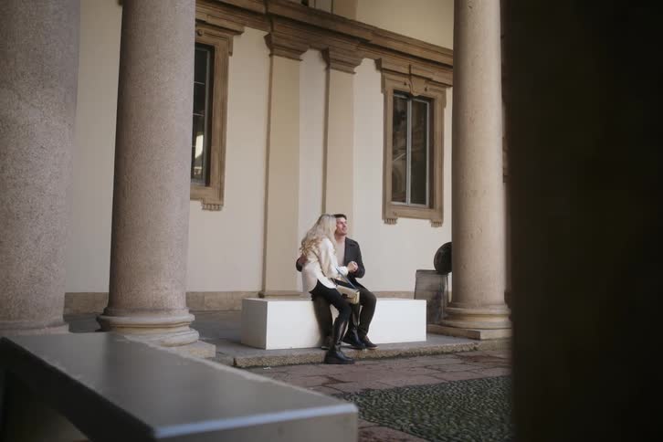 A couple kiss while sitting next to a pillar