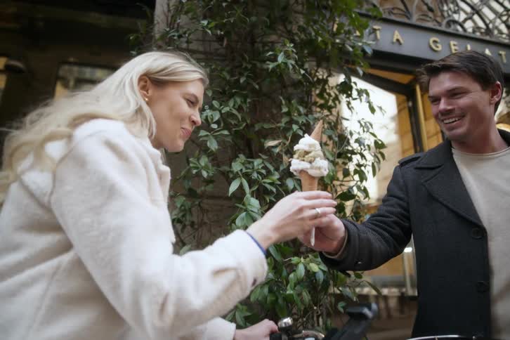 Smiling man handing an ice cream to his girlfriend who is also happy