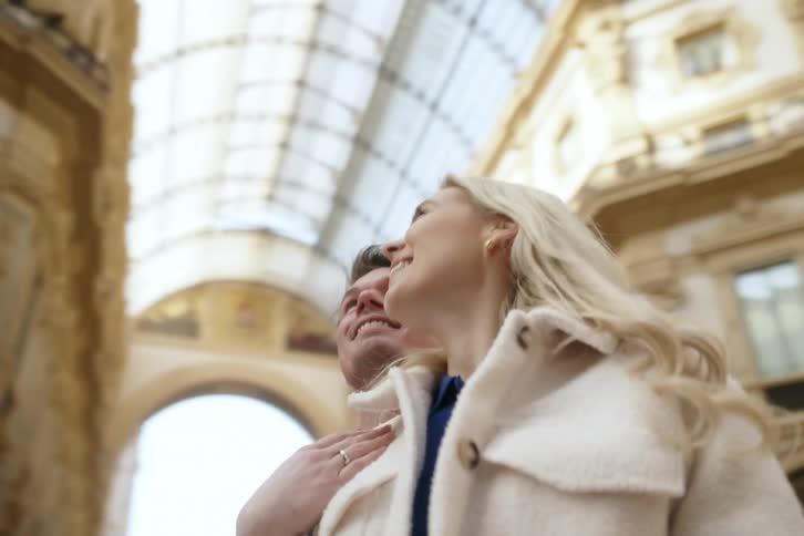 A couple are hugging and looking up at the skylight in the landmark