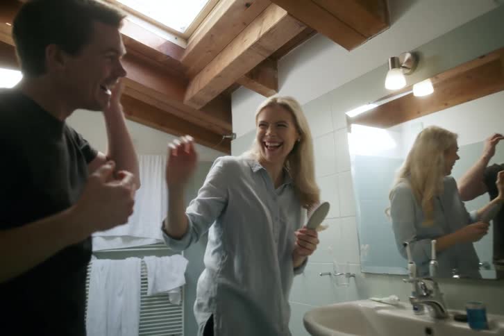 A couple laugh and play in the bathroom